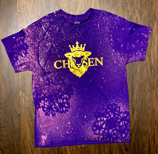 Purple t-shirt with yellow graphic and text on a wooden surface