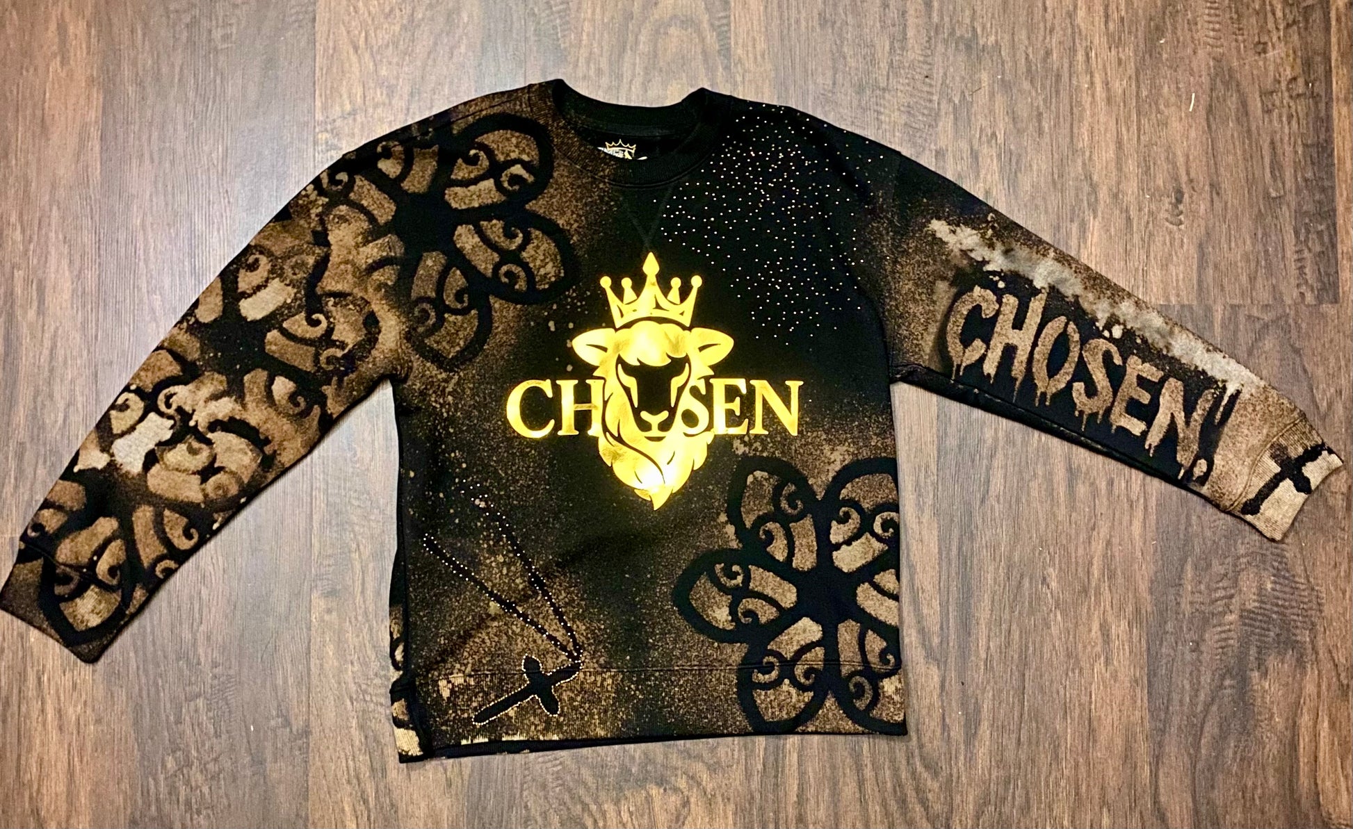Long-sleeve shirt with gold and black design on a wooden surface