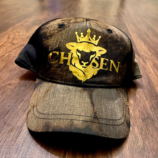 Brown cap with gold logo and text on a wooden surface