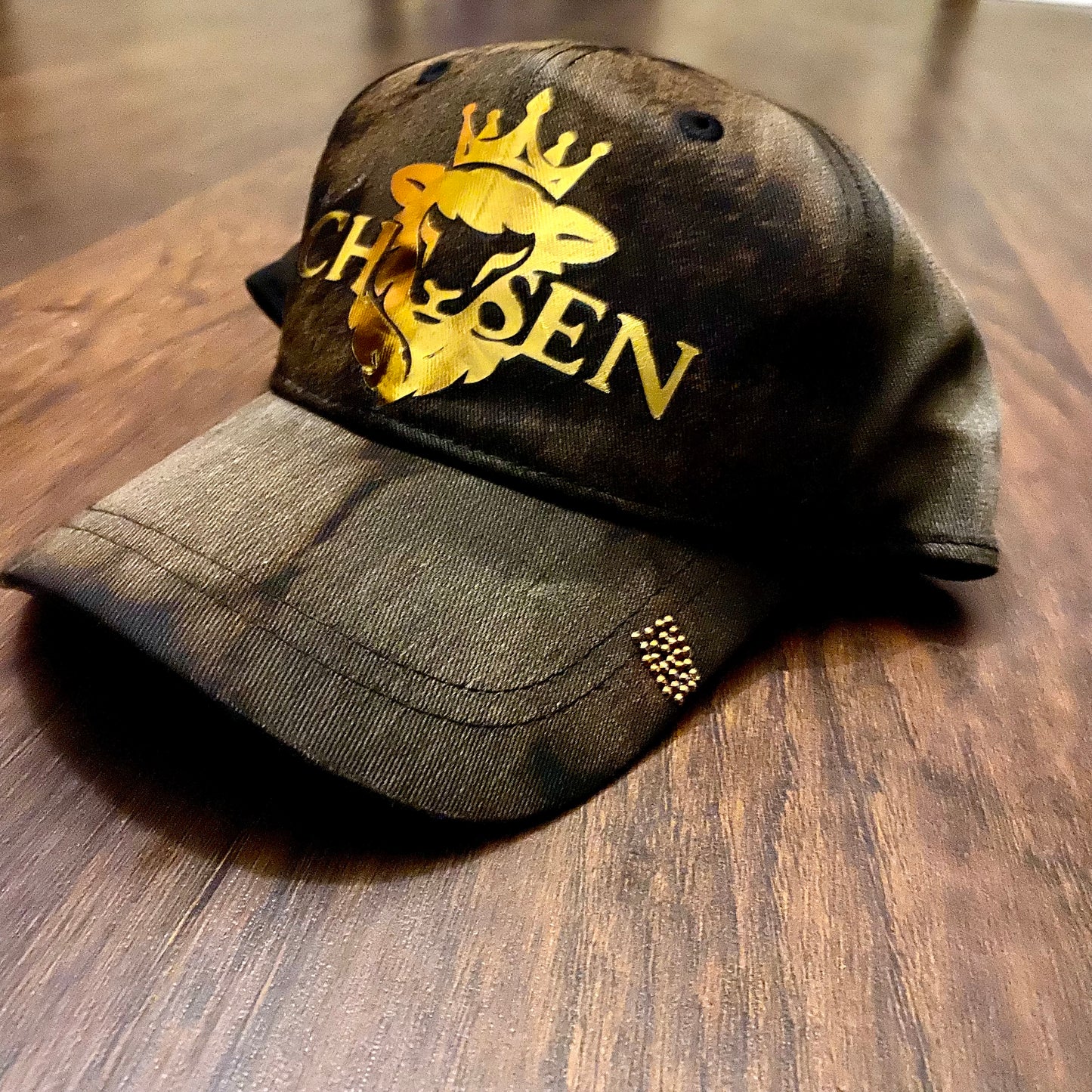 Dark green cap with gold logo and text on a wooden surface