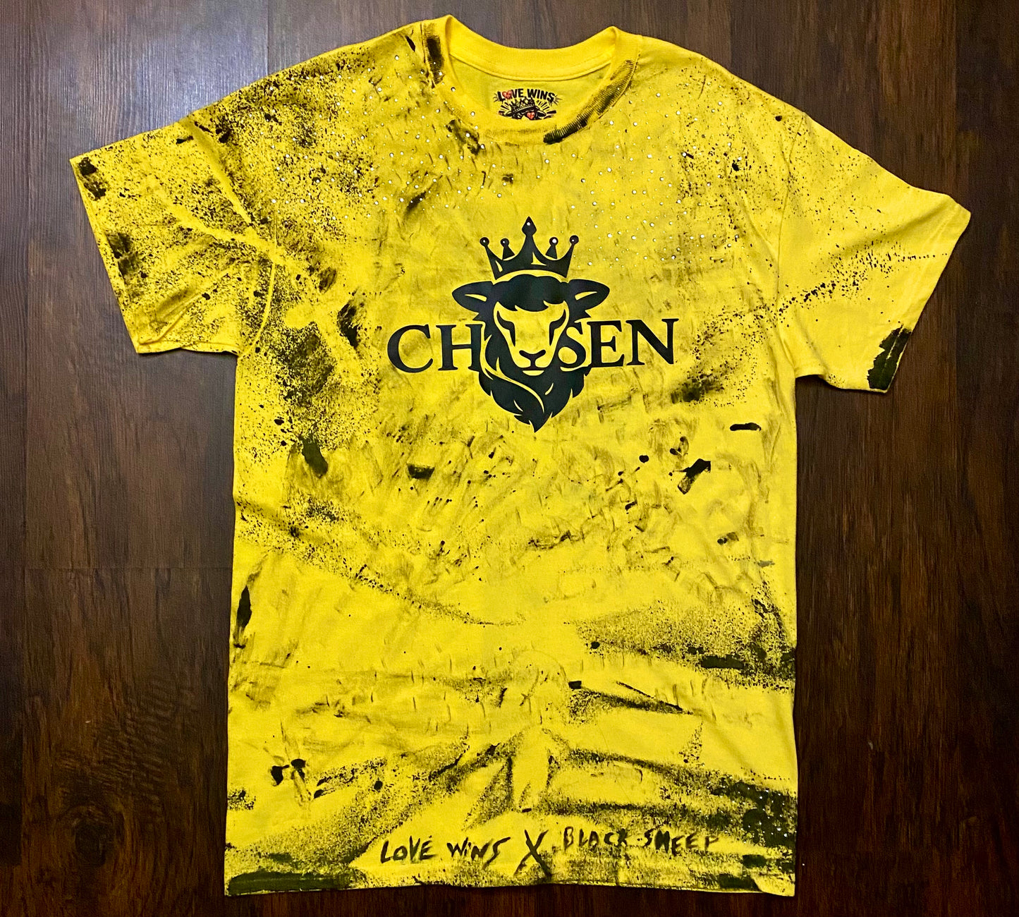 Yellow t-shirt with black graphic design on a wooden surface black sheep